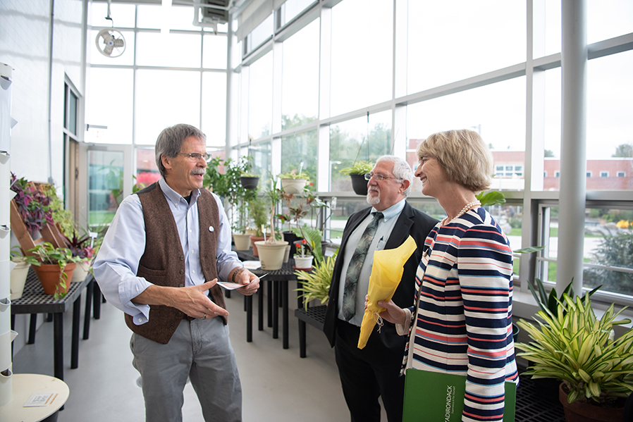Professor of Biology Tim Scherbatskoy, left, talks to Associate Vice President of Facilities Anthony Palangi and Chancellor Kristina Johnson in the greenhouse in Adirondack Hall during an Oct. 12 tour of SUNY Adirondack.
