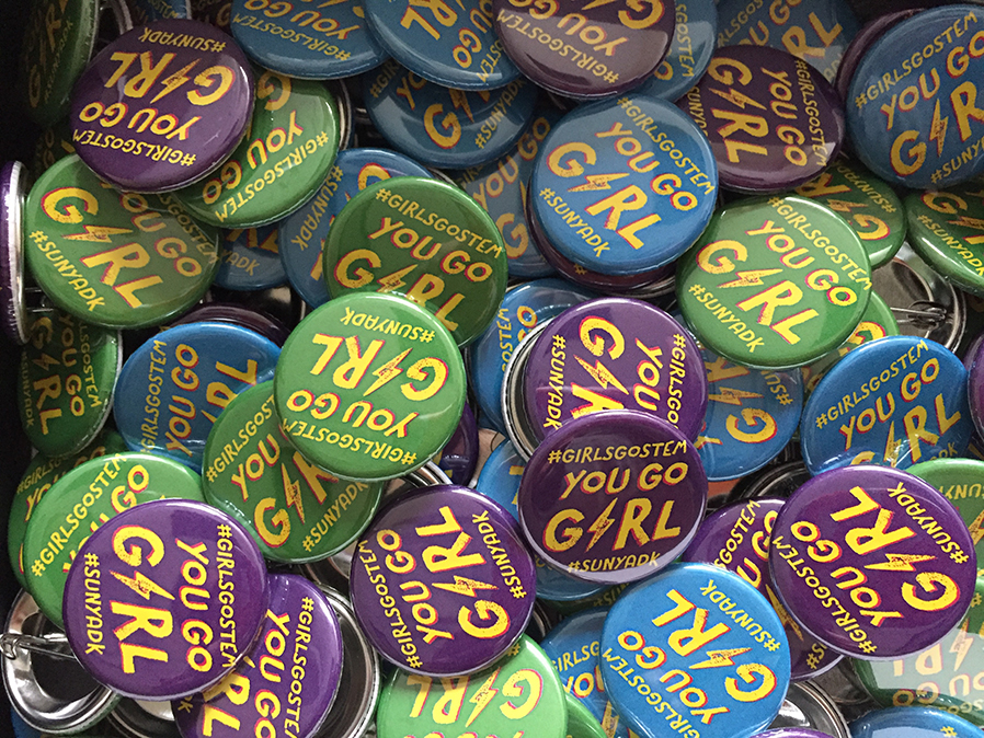 A box of buttons advertise the Girls Go Stem event.