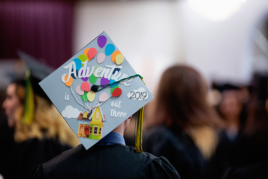 Student wears graduation cap reading 'Adventure is out there: 2019.'