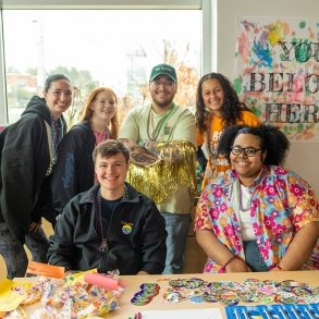 A group of students and staff pose for a photo surrounded by messages of acceptance during the Out of the Darkness Suicide Awareness event on campus