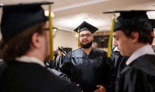 A graduate is seen smiling while lining up for commencement