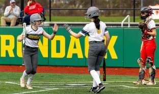 Softball players slap a high-five during a game in the 2025 season.