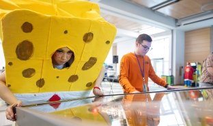 Someone dressed as SpongeBob SquarePants plays an arcade-style video game