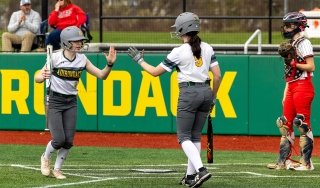 Softball players slap a high-five during a game in the 2025 season.
