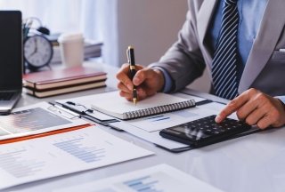 Man in suit at desk with calculator and notepad