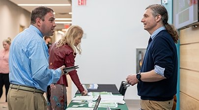 Brian Holtz, right, speaks with an attendee at a job fair