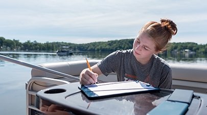 A student logs data during a research trip on Glen Lake.