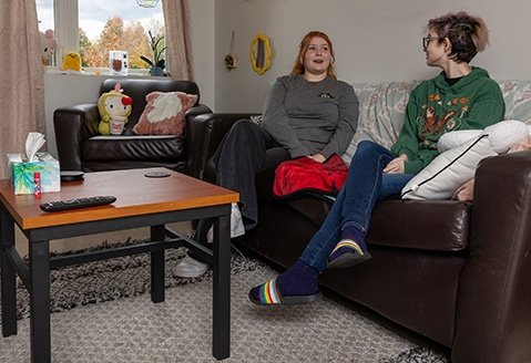 Two students share a laugh while sitting on the sofa in a Residence Hall room.