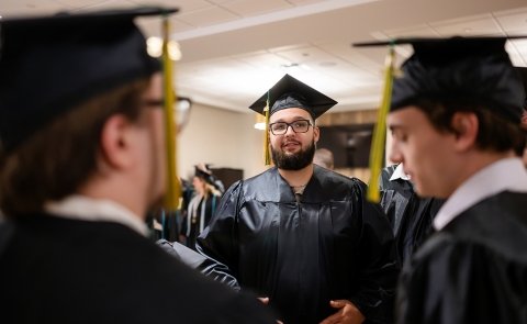 A graduate is seen smiling while lining up for commencement
