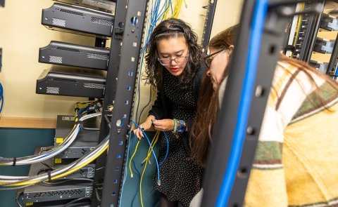 Two students work on a project in a networking lab