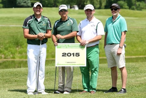 A group of male golfers dressed festively in green pose for a team shot in the 2015 tournament