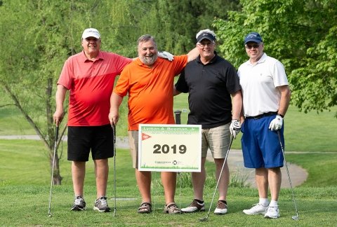 A group of four male golfers pose for a team photo during the 2019 event
